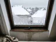 Condens pe marginea de jos a unei ferestre de mansardă într-o dimineață de iarnă