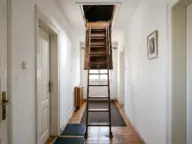 Scară escamotabilă din lemn desfăcută din tavanul unui hol