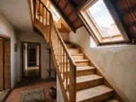 Scară spre mansardă luminată de o fereastră de acoperiș deasupra golului